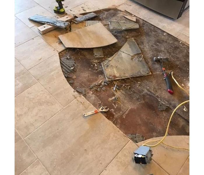 tile flooring torn up to reveal water damage